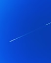 a jet flying through a blue sky with a contrail