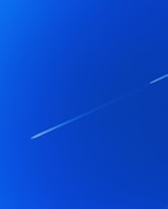 a jet flying through a blue sky with a contrail
