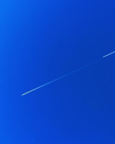 a jet flying through a blue sky with a contrail