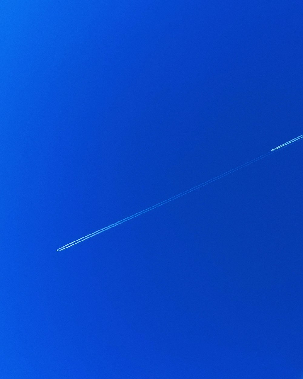 a jet flying through a blue sky with a contrail