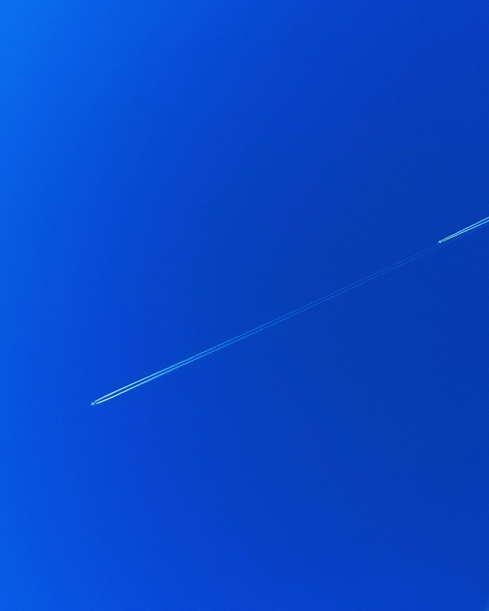 a jet flying through a blue sky with a contrail