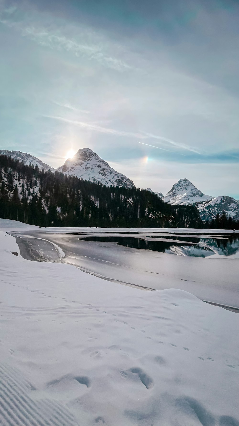 the sun is shining over a snowy mountain range