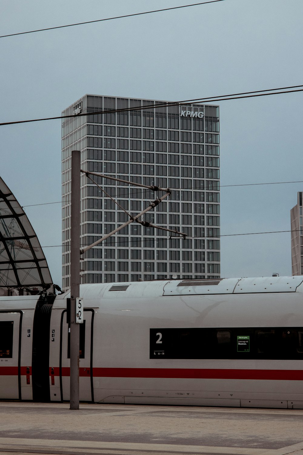 Ein weiß-roter Zug fährt an einem hohen Gebäude vorbei