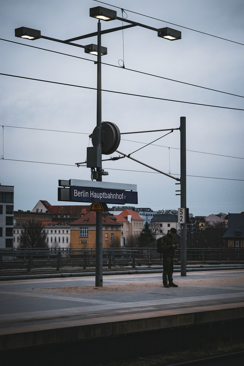 a man standing on a train platform next to a street sign
