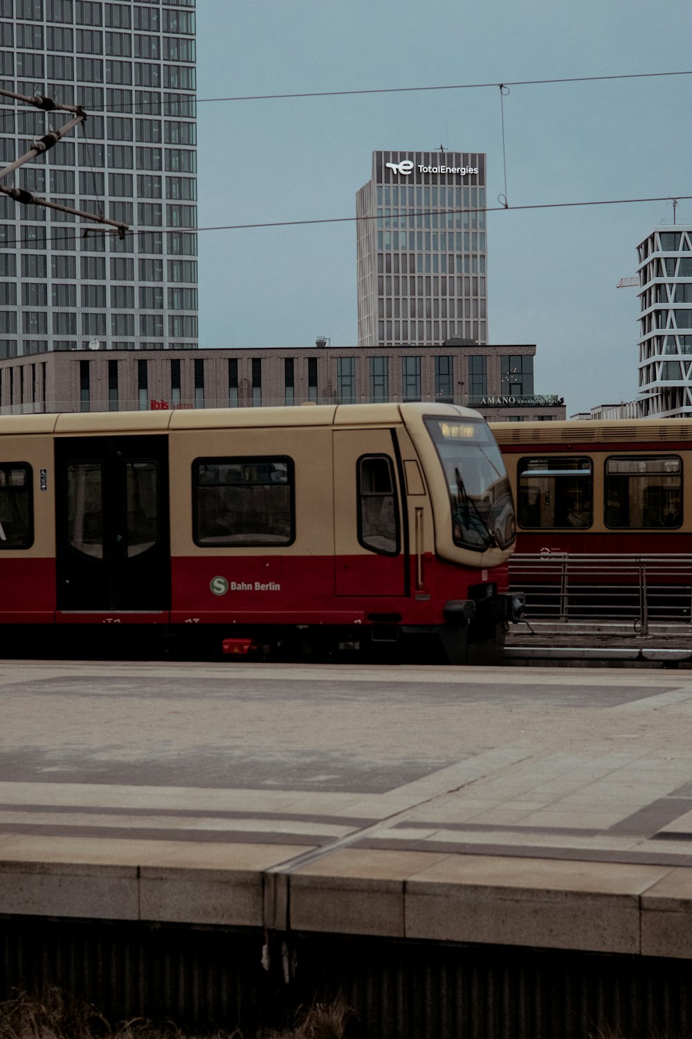 a red and white train traveling past tall buildings