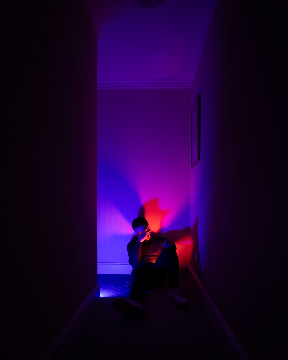 a person sitting in a dark room with a purple light
