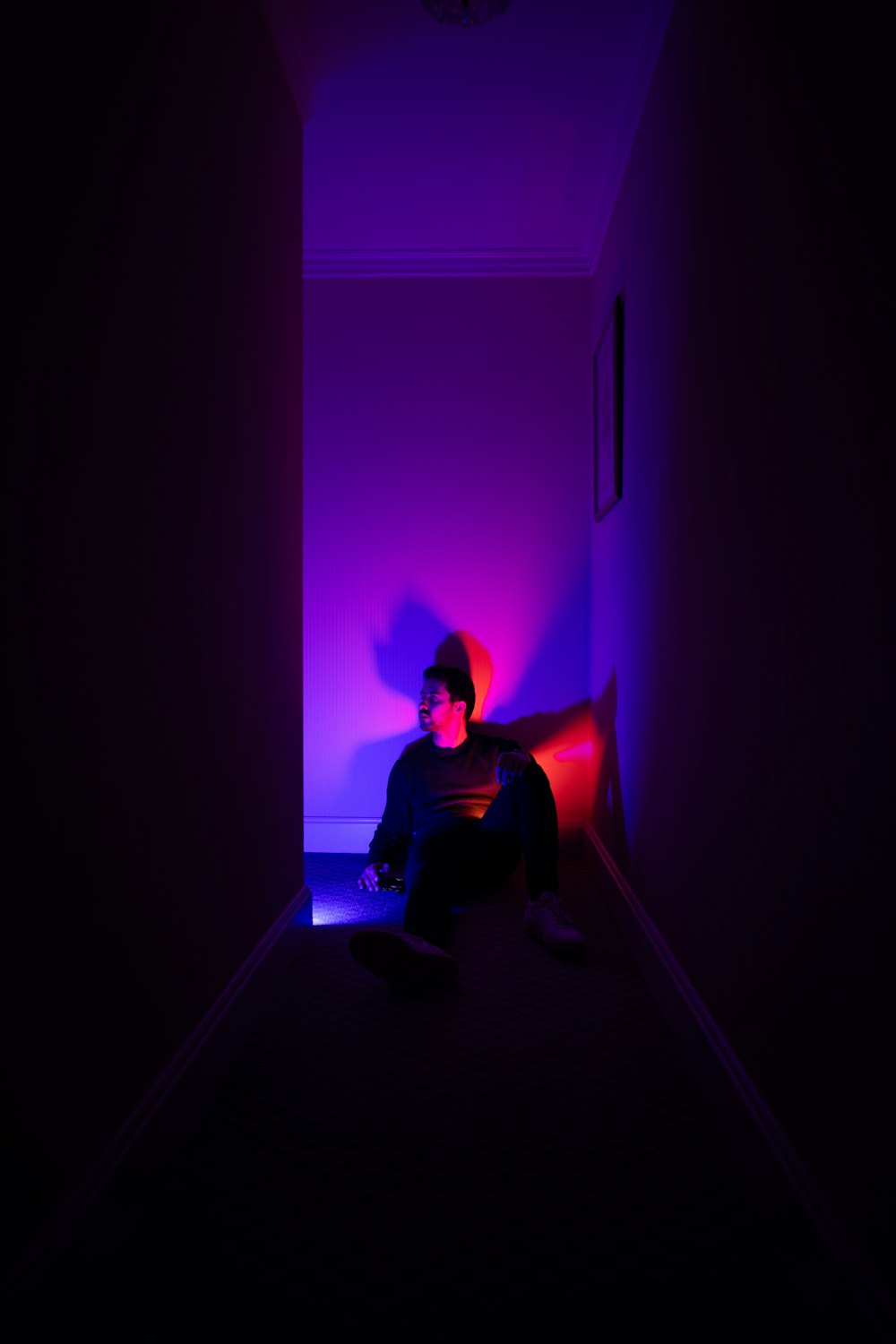 a person sitting in a dark room with a purple light