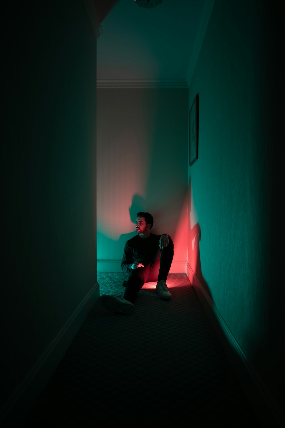 a man sitting on the floor in a dark hallway