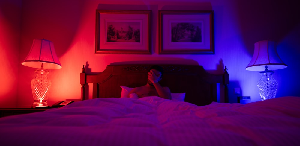 a person laying in a bed with two lamps on either side of the bed