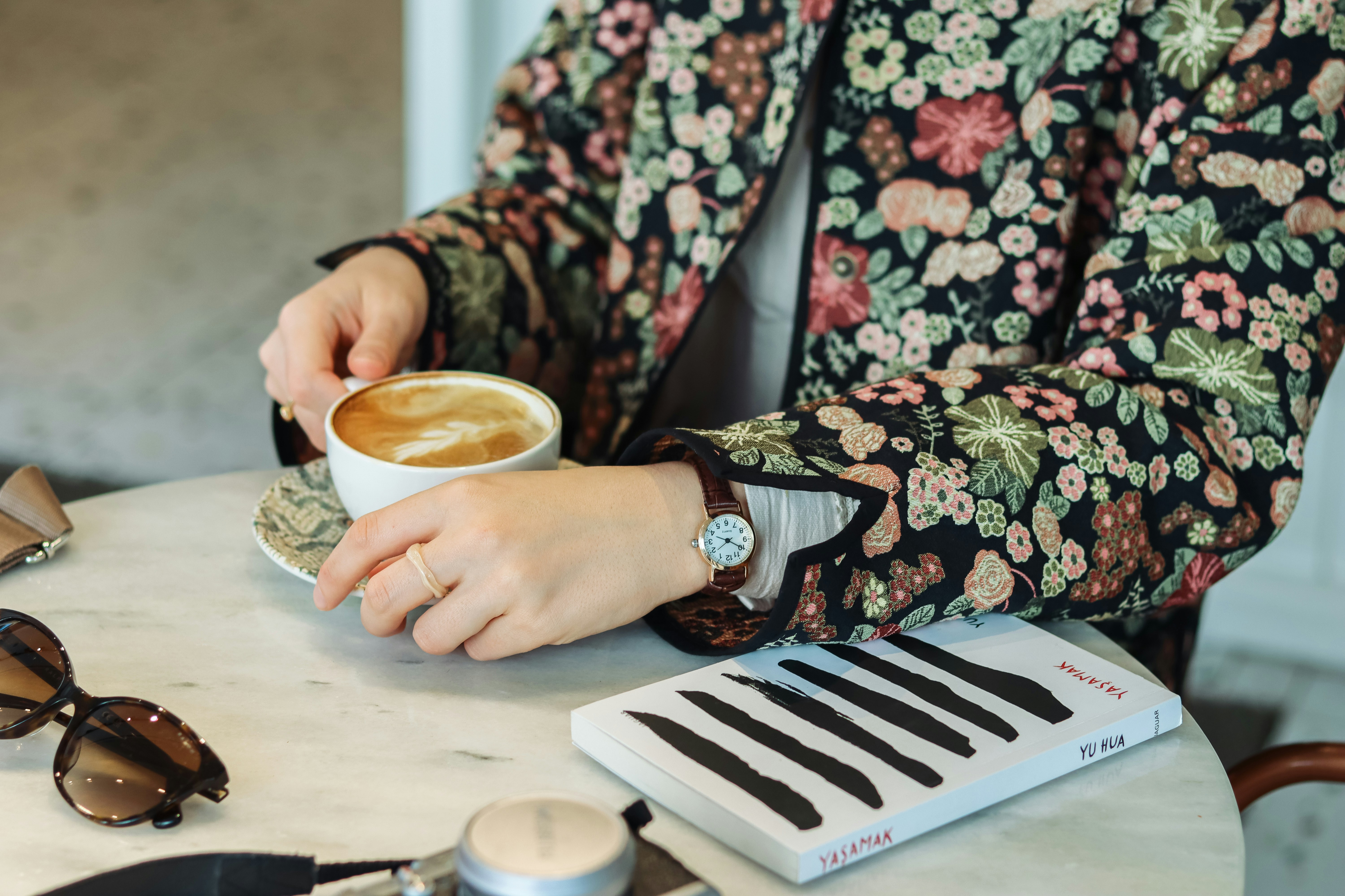 a woman sitting at a table with a cup of coffee