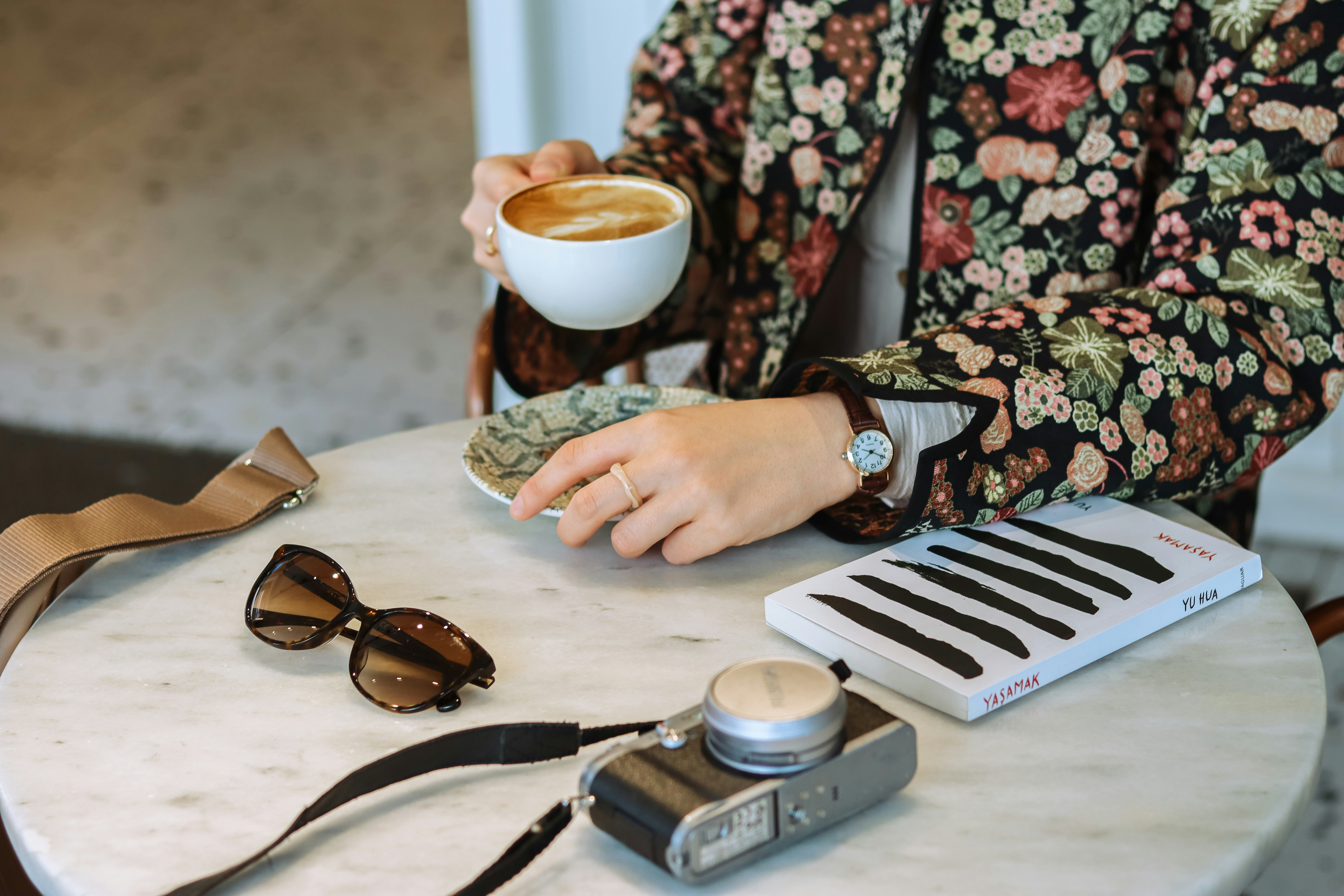 a woman sitting at a table with a cup of coffee