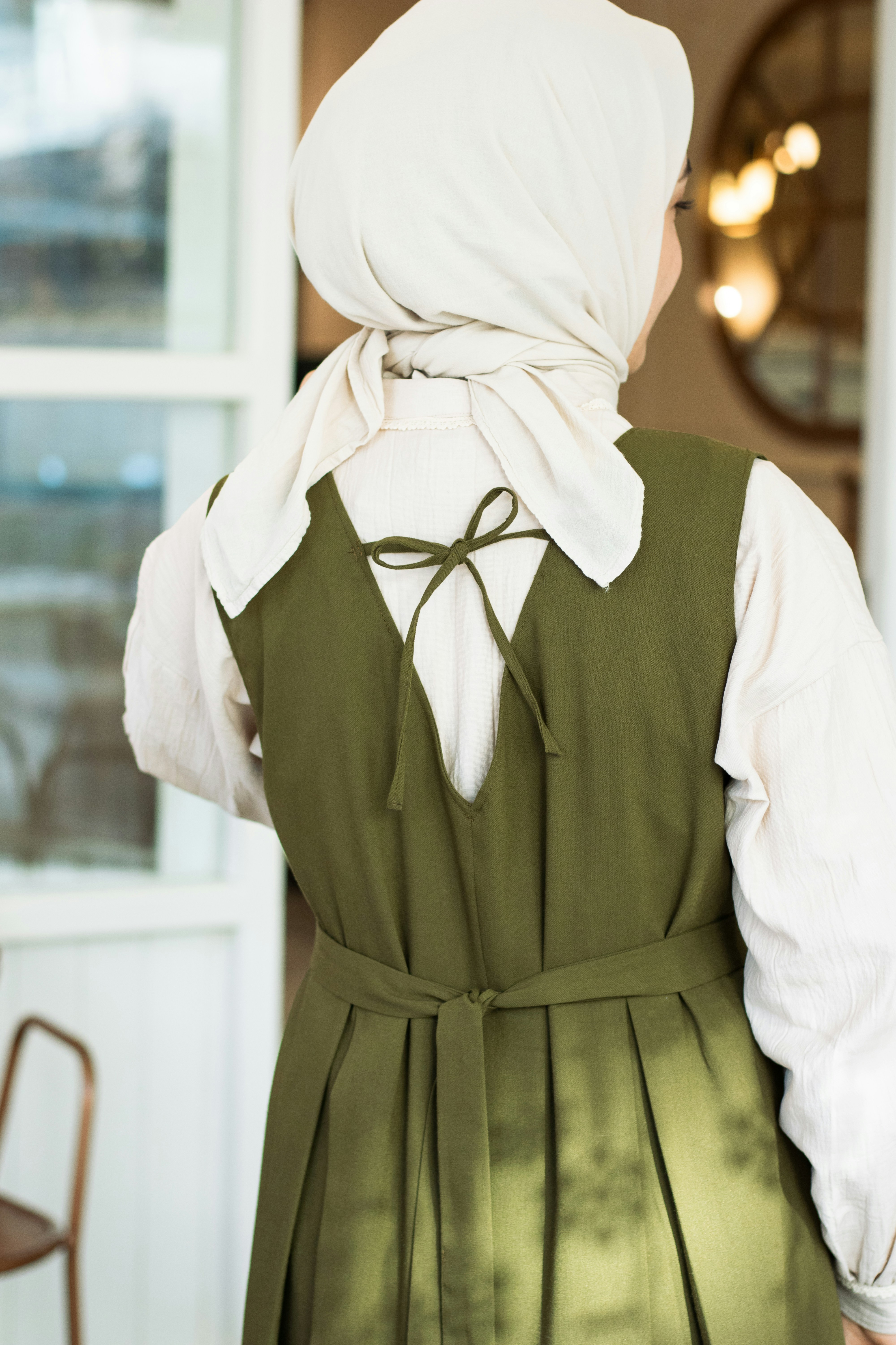 a woman wearing a green dress and a white head scarf