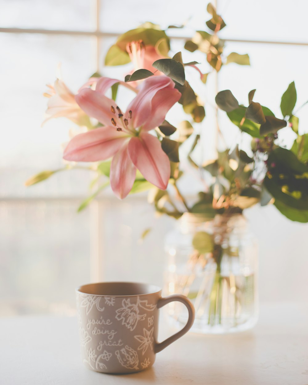 un vaso di fiori seduto accanto a una tazza su un tavolo