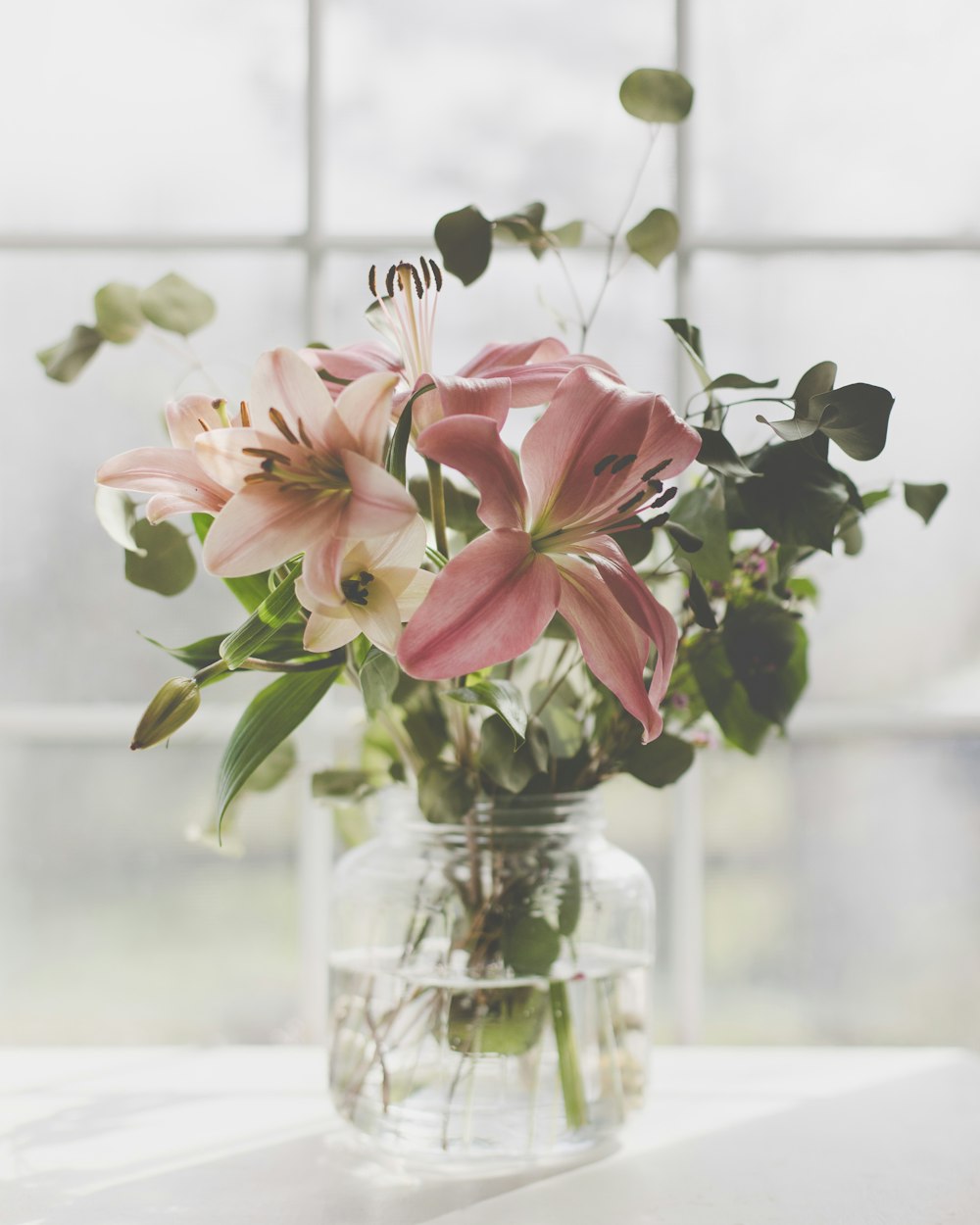 un vase rempli de fleurs roses sur le dessus d’une table