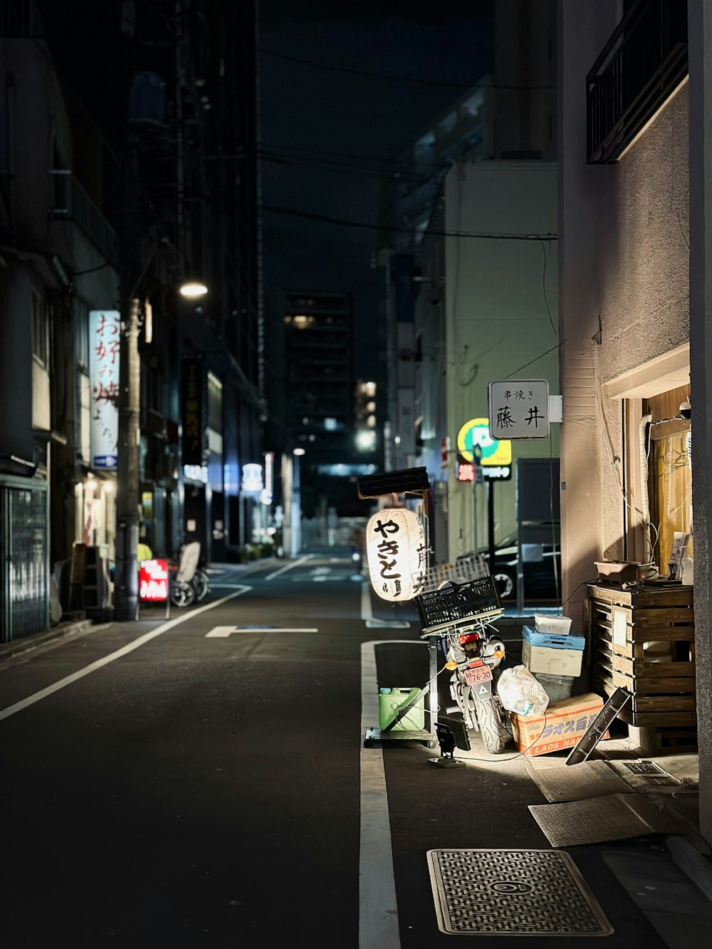 a city street at night with a trash can on the side of the road