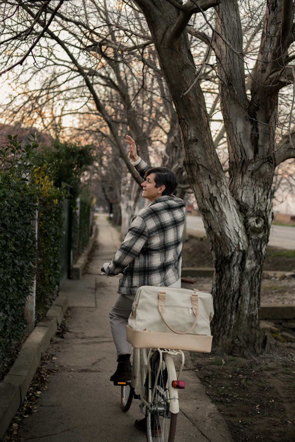 a man riding a bike down a sidewalk next to a tree