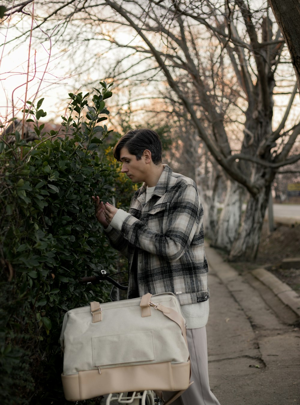 a man holding onto a bag next to a bush