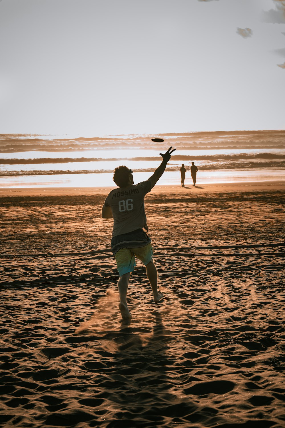 a man standing on top of a sandy beach next to the ocean