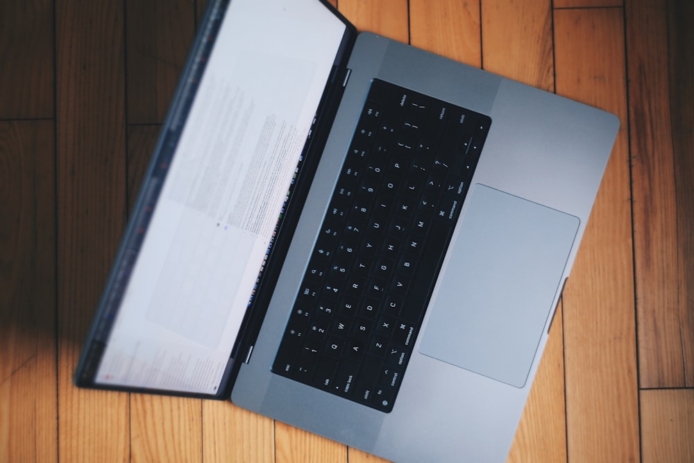 an open laptop computer sitting on top of a wooden floor