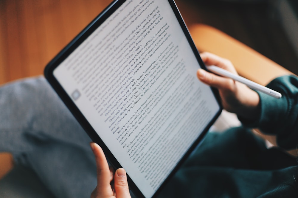 a person holding a tablet with a pen in their hand