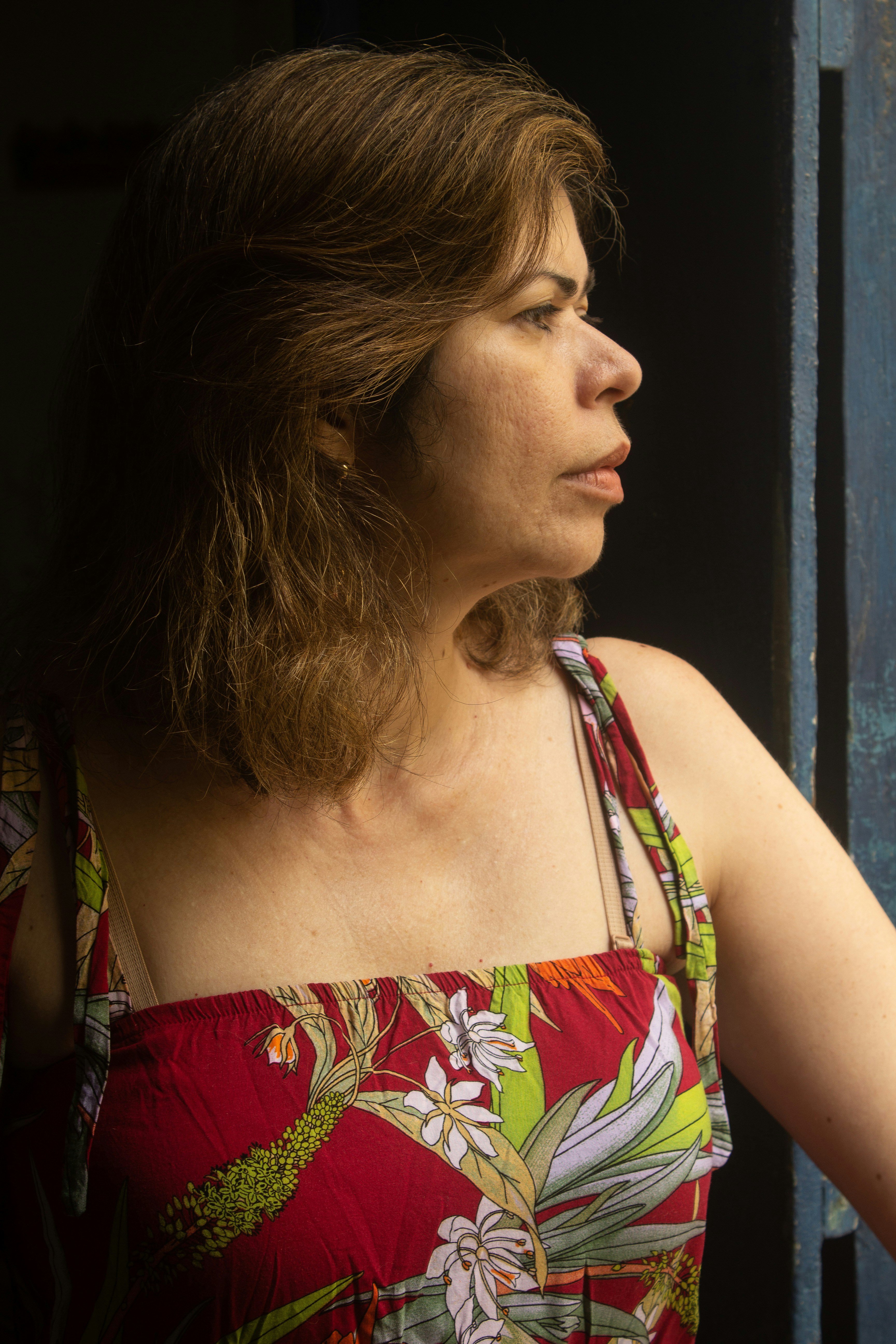 a woman in a floral dress looking out a window
