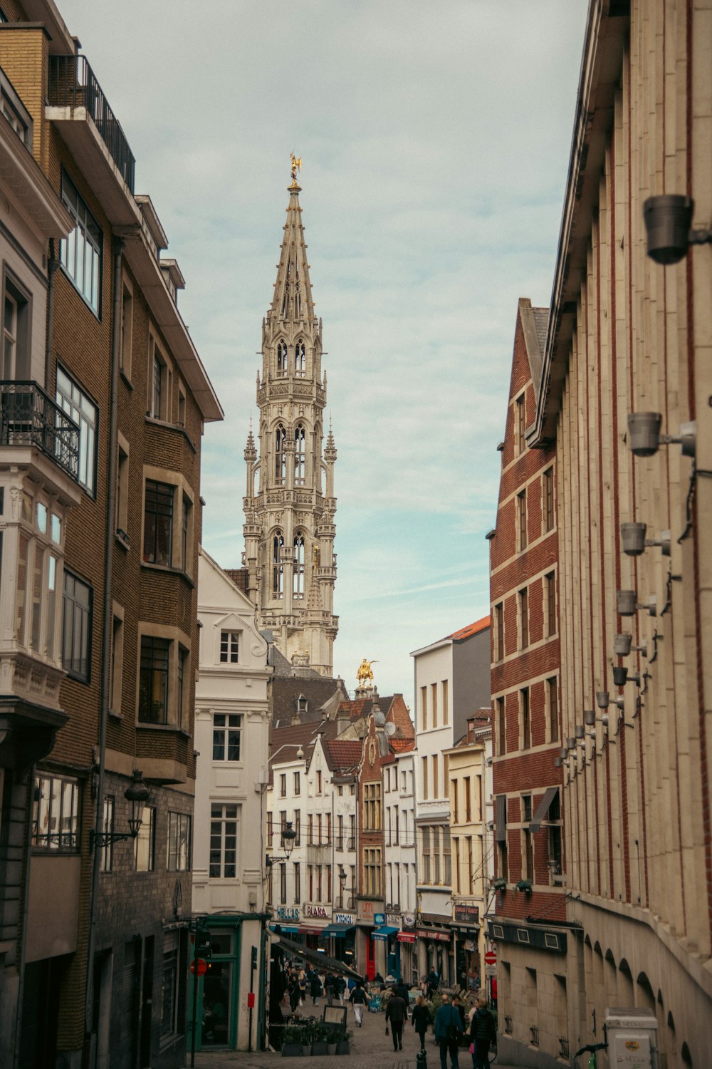 a city street lined with tall buildings with a clock tower in the background