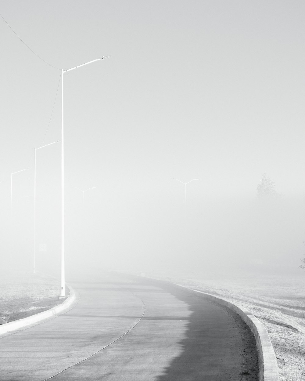 a black and white photo of a foggy road