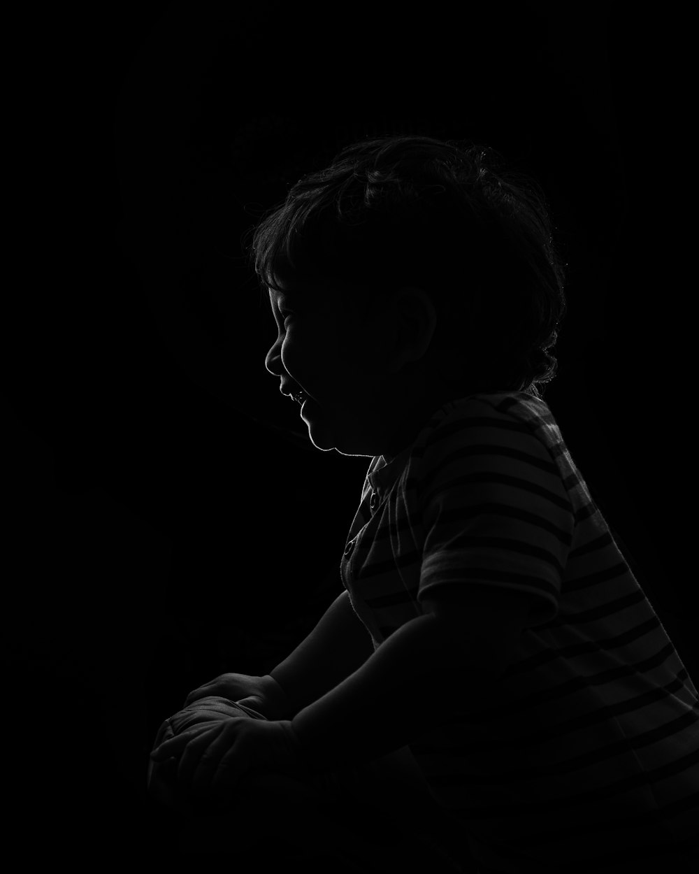a little boy sitting down in the dark