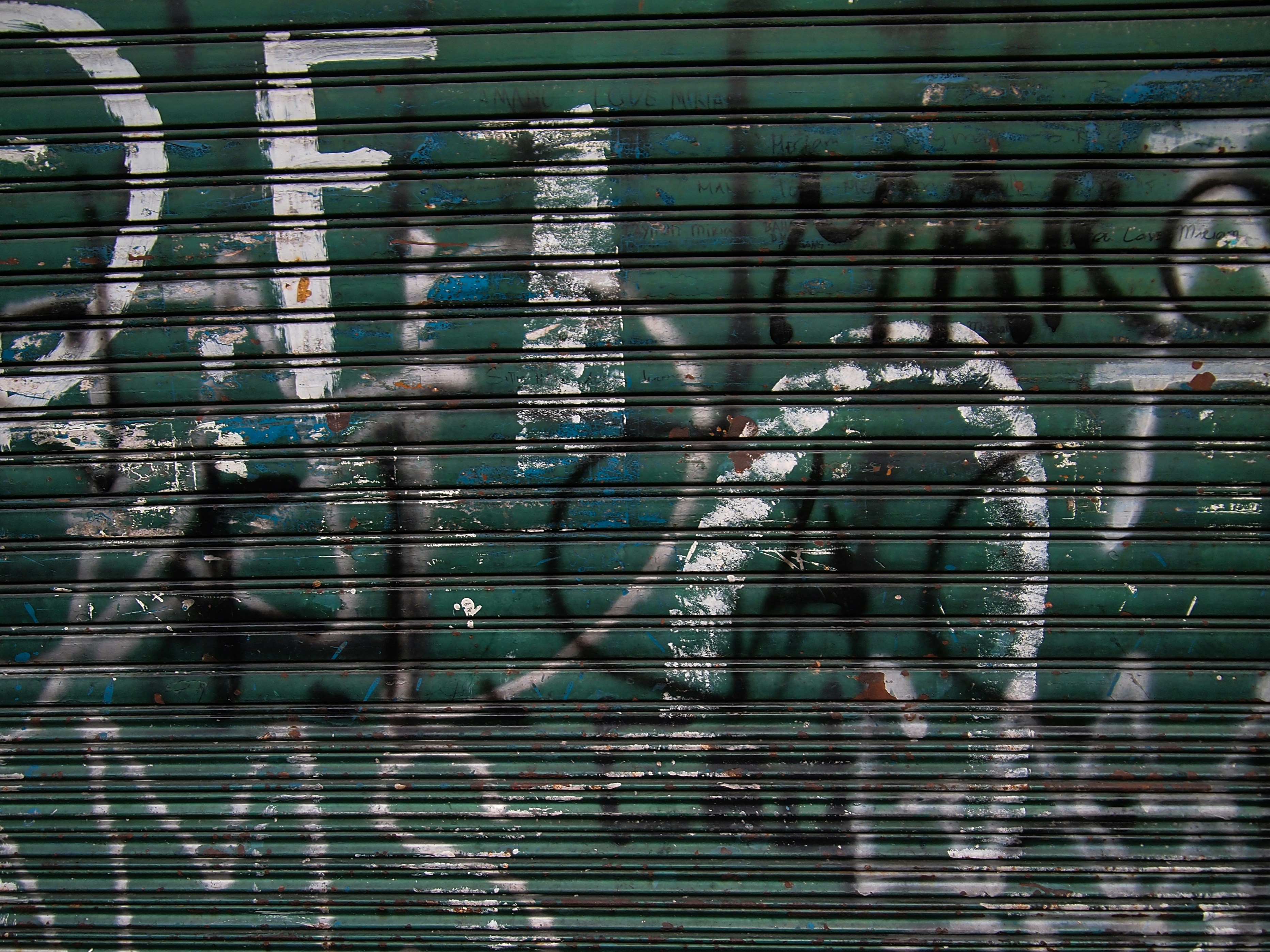 a green garage door with graffiti on it