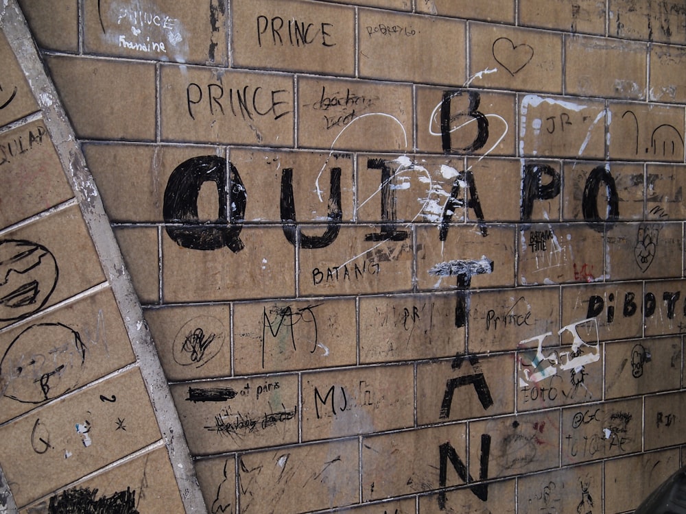 una pared de ladrillo con grafitis escritos en ella