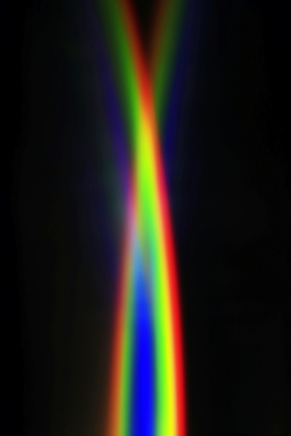 a rainbow colored object in the middle of a black background