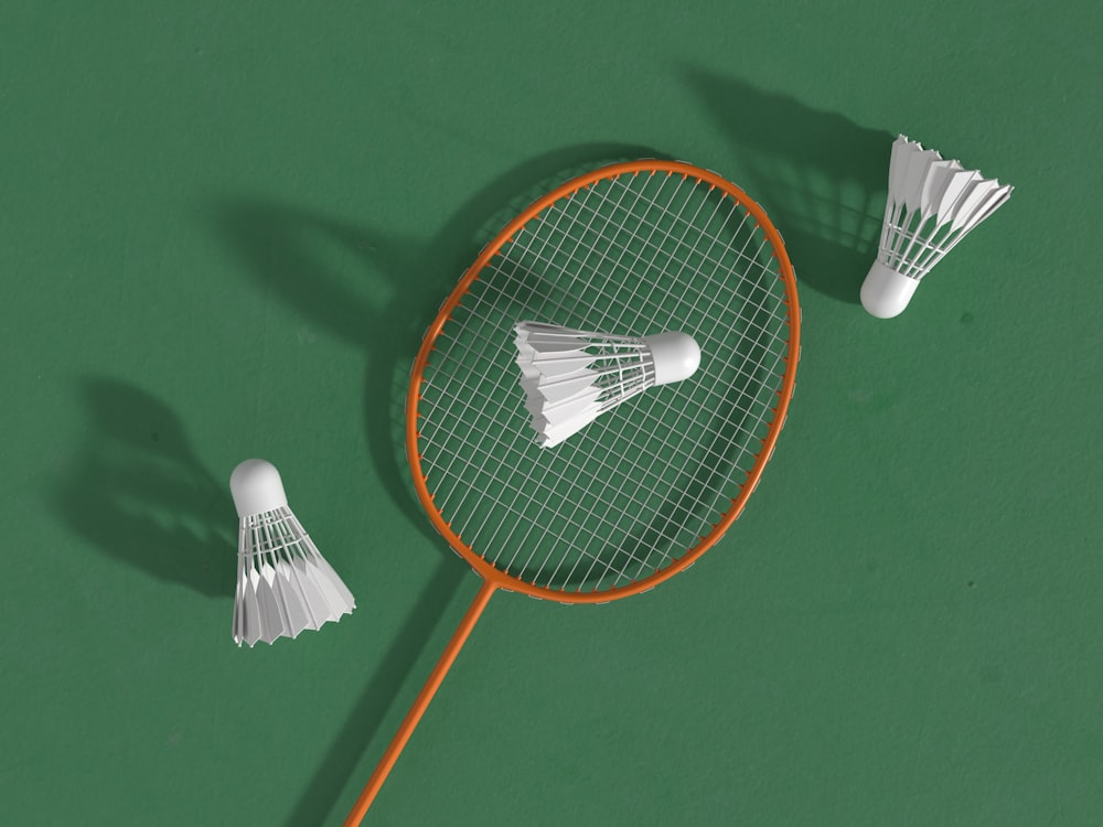 a badminton racket and two shuttles on a green surface