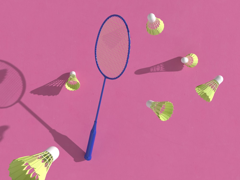 a badminton racket and several badminton balls on a pink background