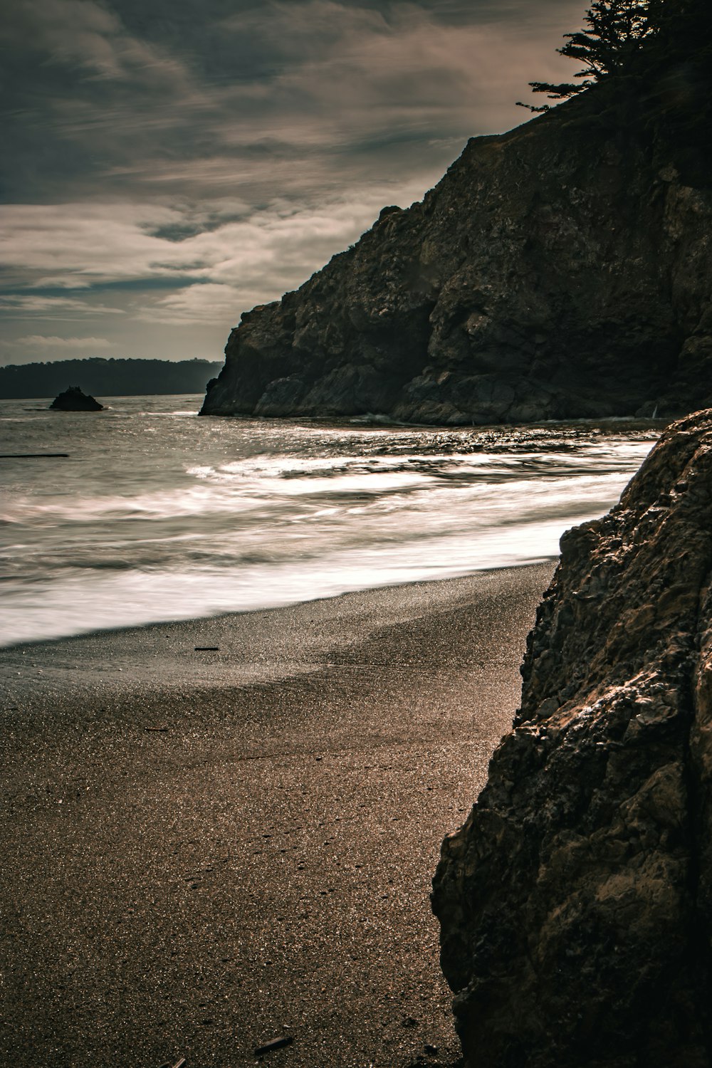 a beach with a rock outcropping next to the ocean