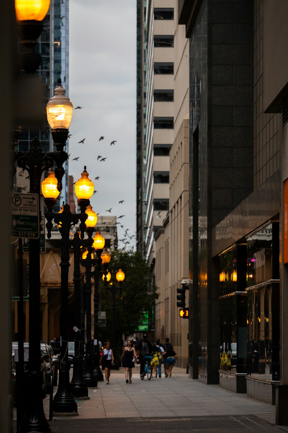 a group of people walking down a street next to tall buildings