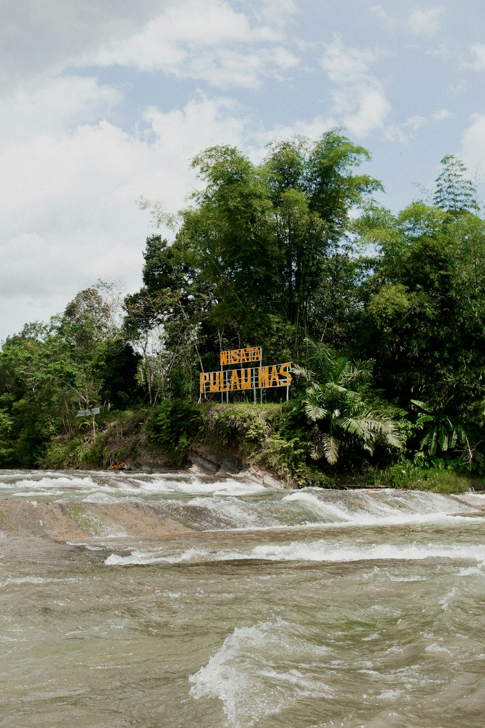 there is a sign that is on a hill above the water