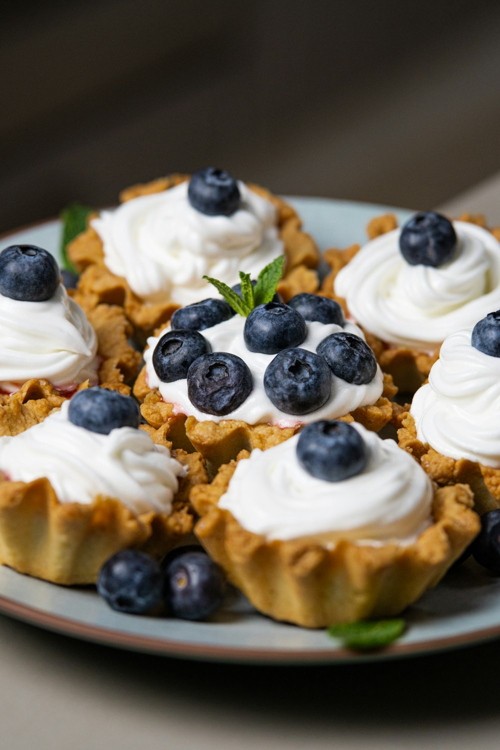 a plate topped with mini pies covered in whipped cream and blueberries