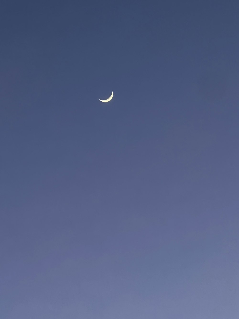 a half moon is seen in a clear blue sky