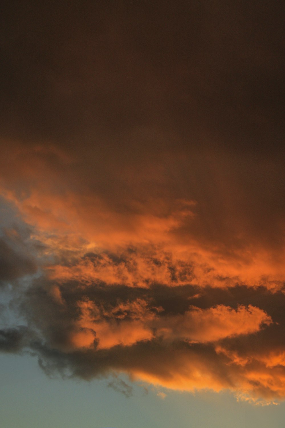 a plane flying through a cloudy sky at sunset