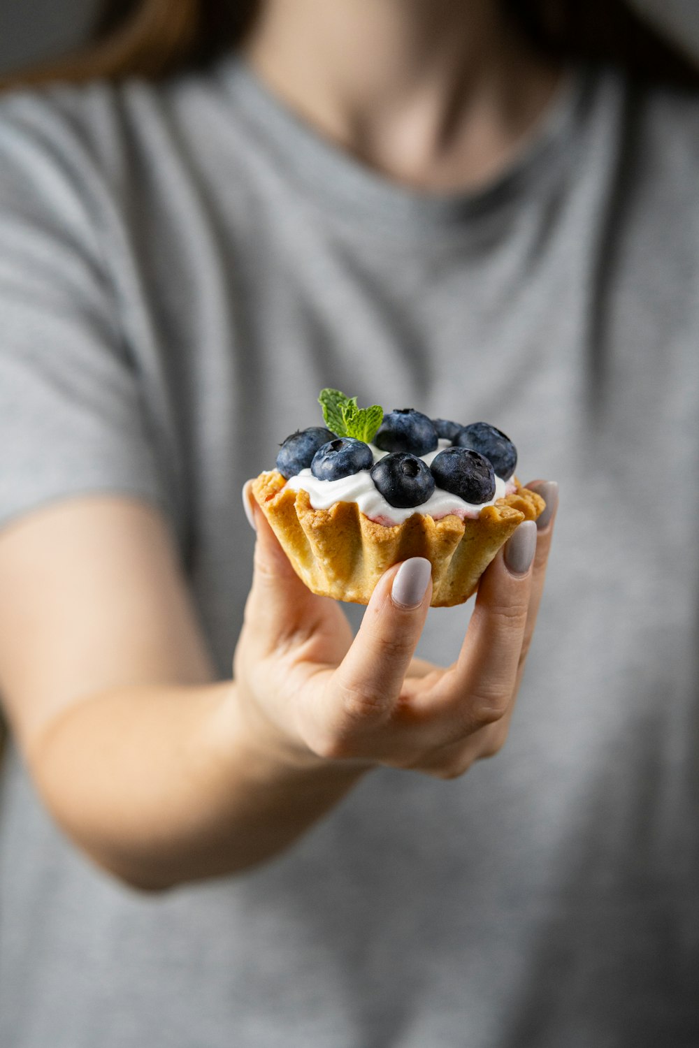 une femme tenant une pâtisserie avec des myrtilles et de la crème