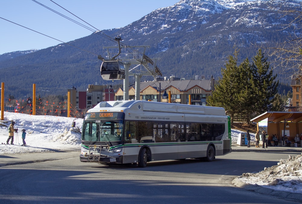 a bus driving down a street next to a snow covered mountain