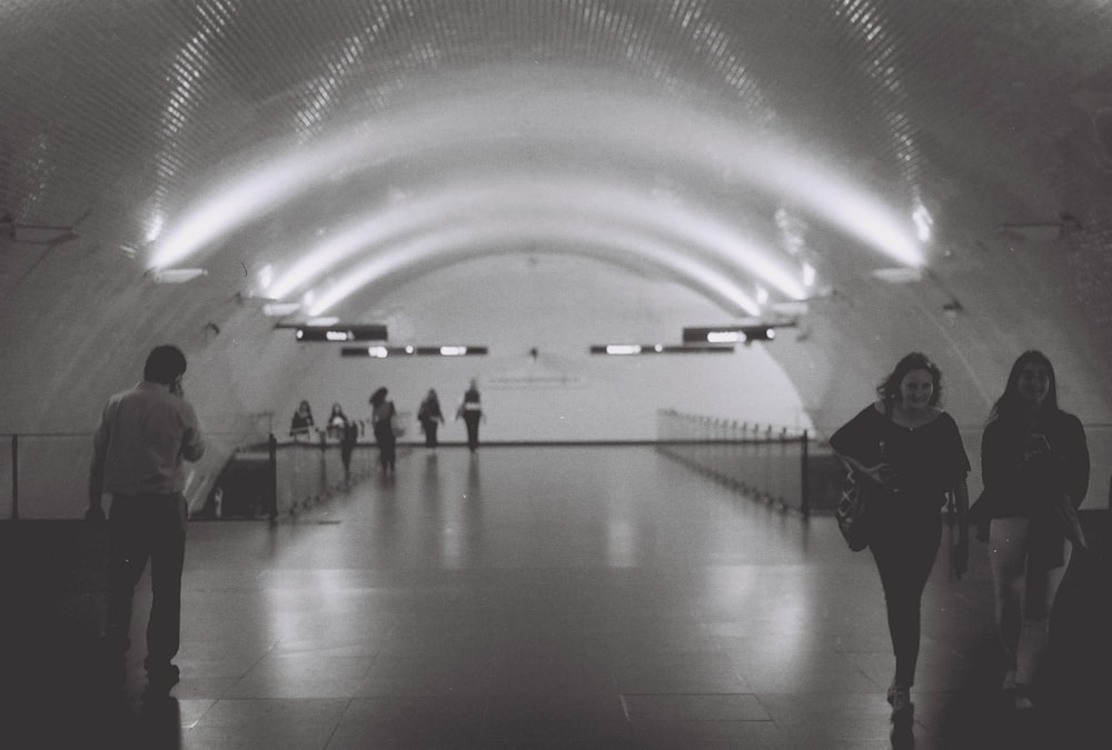 a black and white photo of people walking in a subway