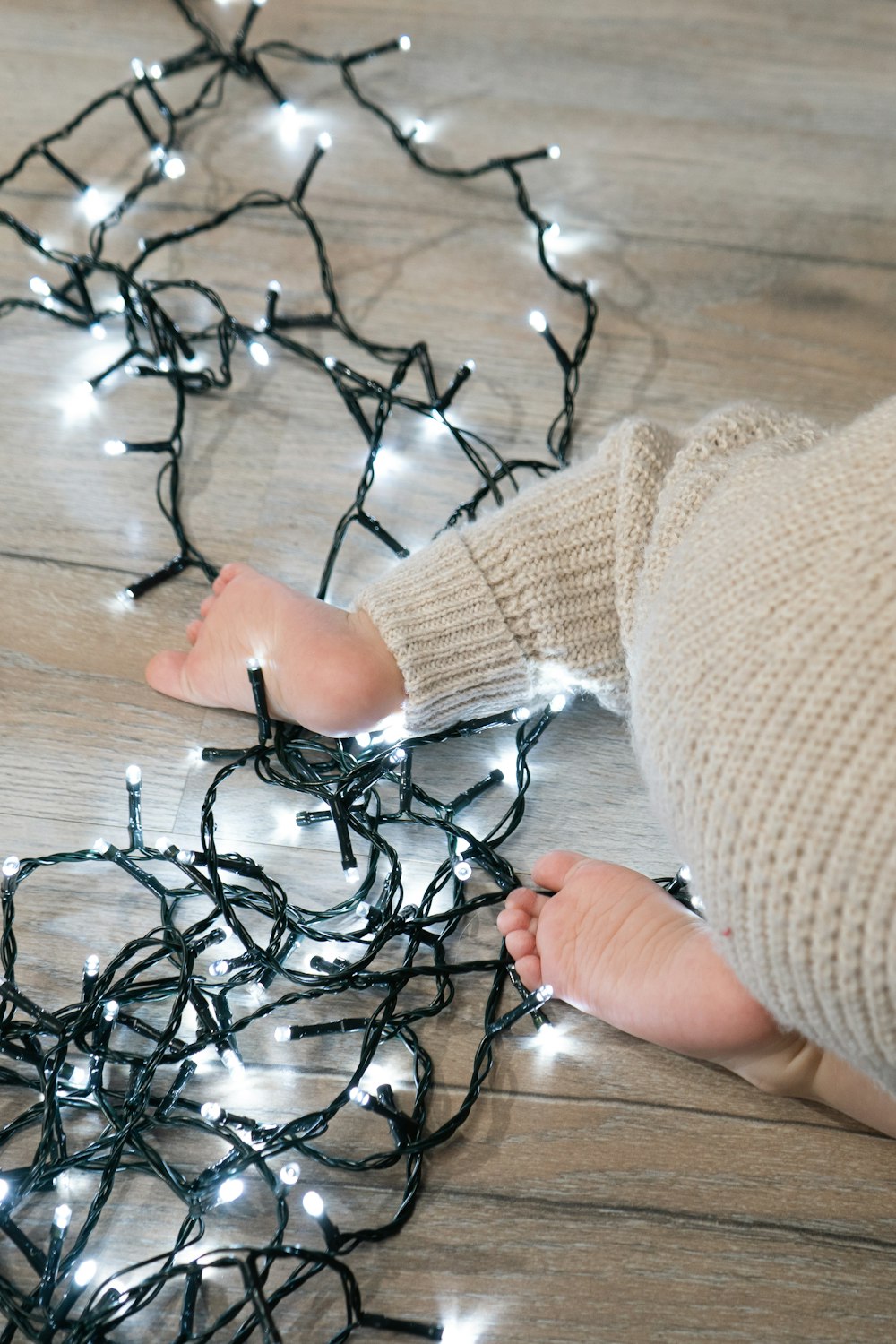 a baby is laying on the floor with a string of lights