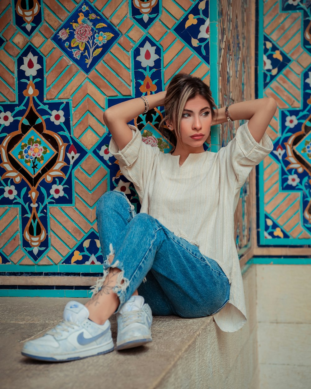 a woman sitting on the ground with her hands behind her head