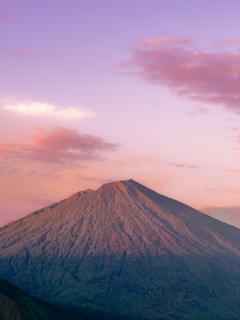 a very tall mountain with a pink sky in the background