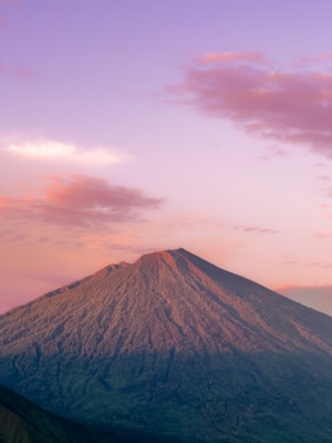 a very tall mountain with a pink sky in the background