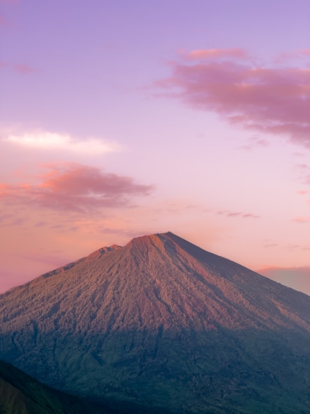 a very tall mountain with a pink sky in the background