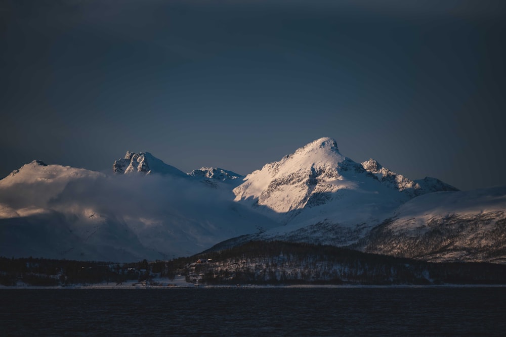 a snow covered mountain with a body of water in the foreground