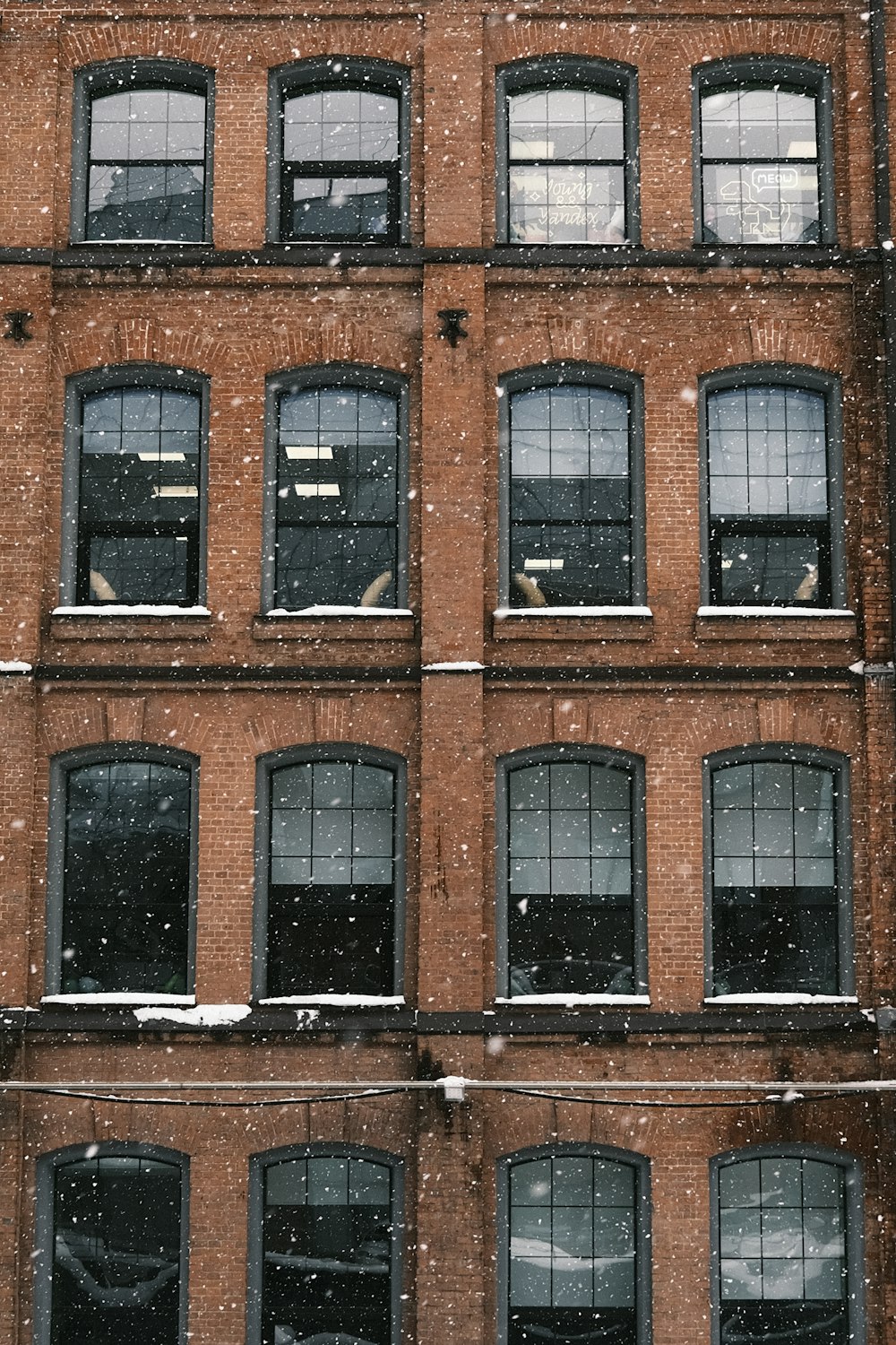 a tall brick building with many windows covered in snow
