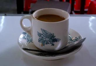 a cup of coffee on a saucer with a spoon